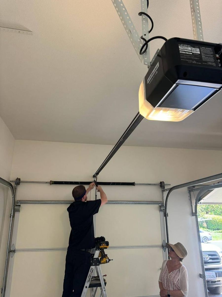 Technician servicing a garage door opener rail