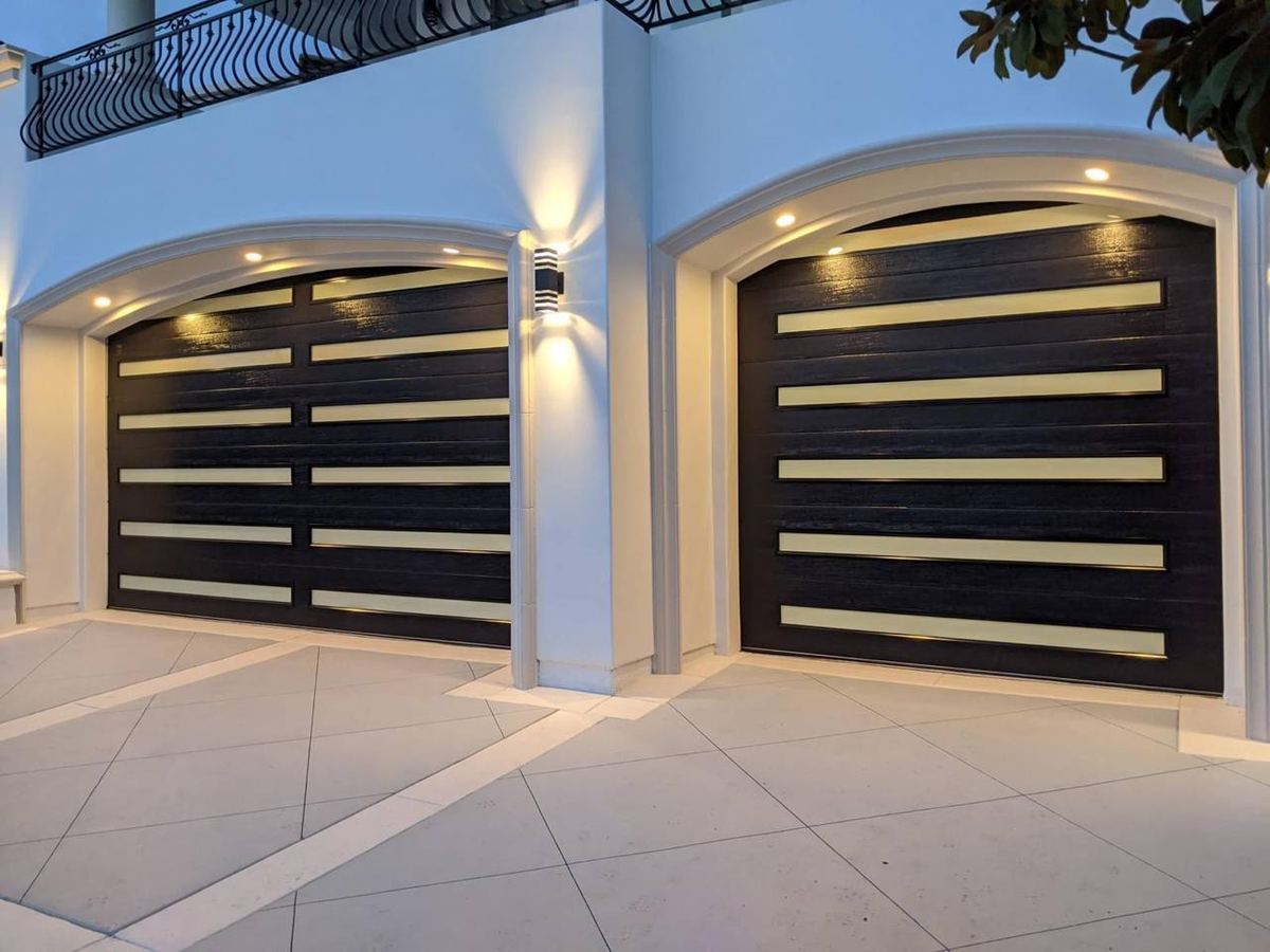 Modern black glass-panel garage doors on a stucco home